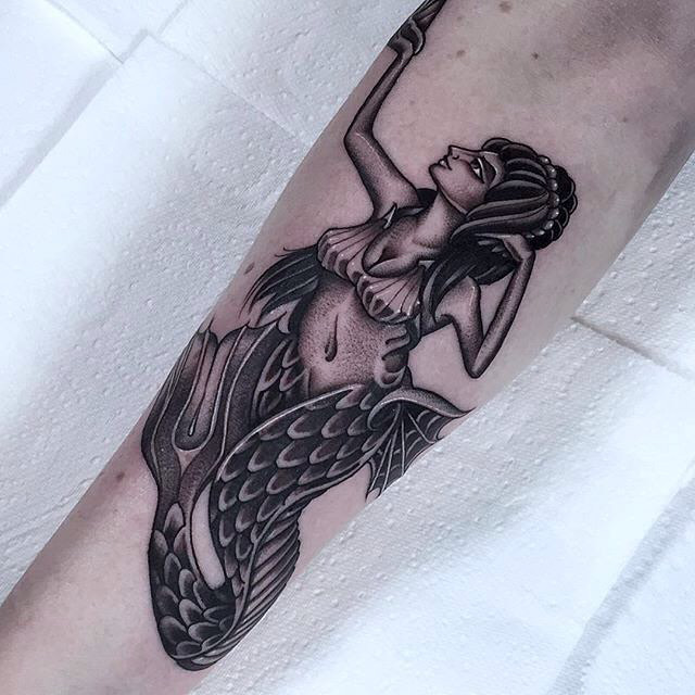 arm tattoo of a black and grye mermaid