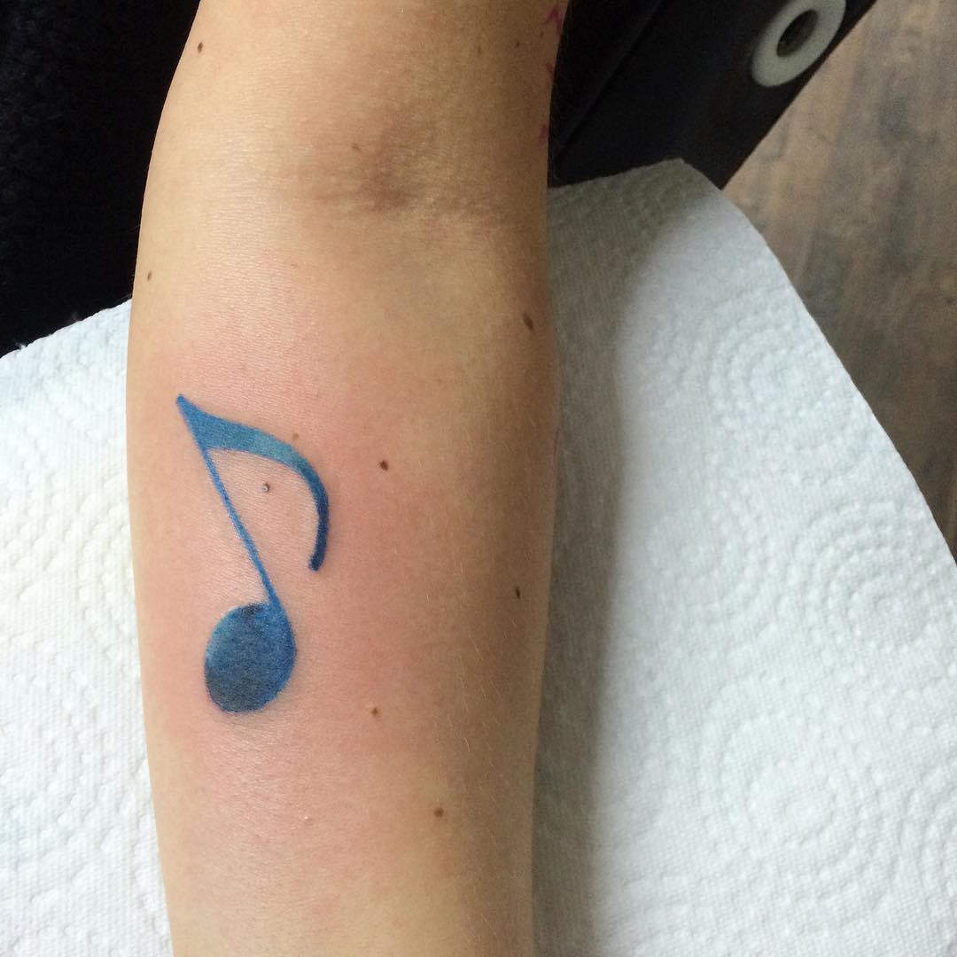 small note tattoo on arm, blue color