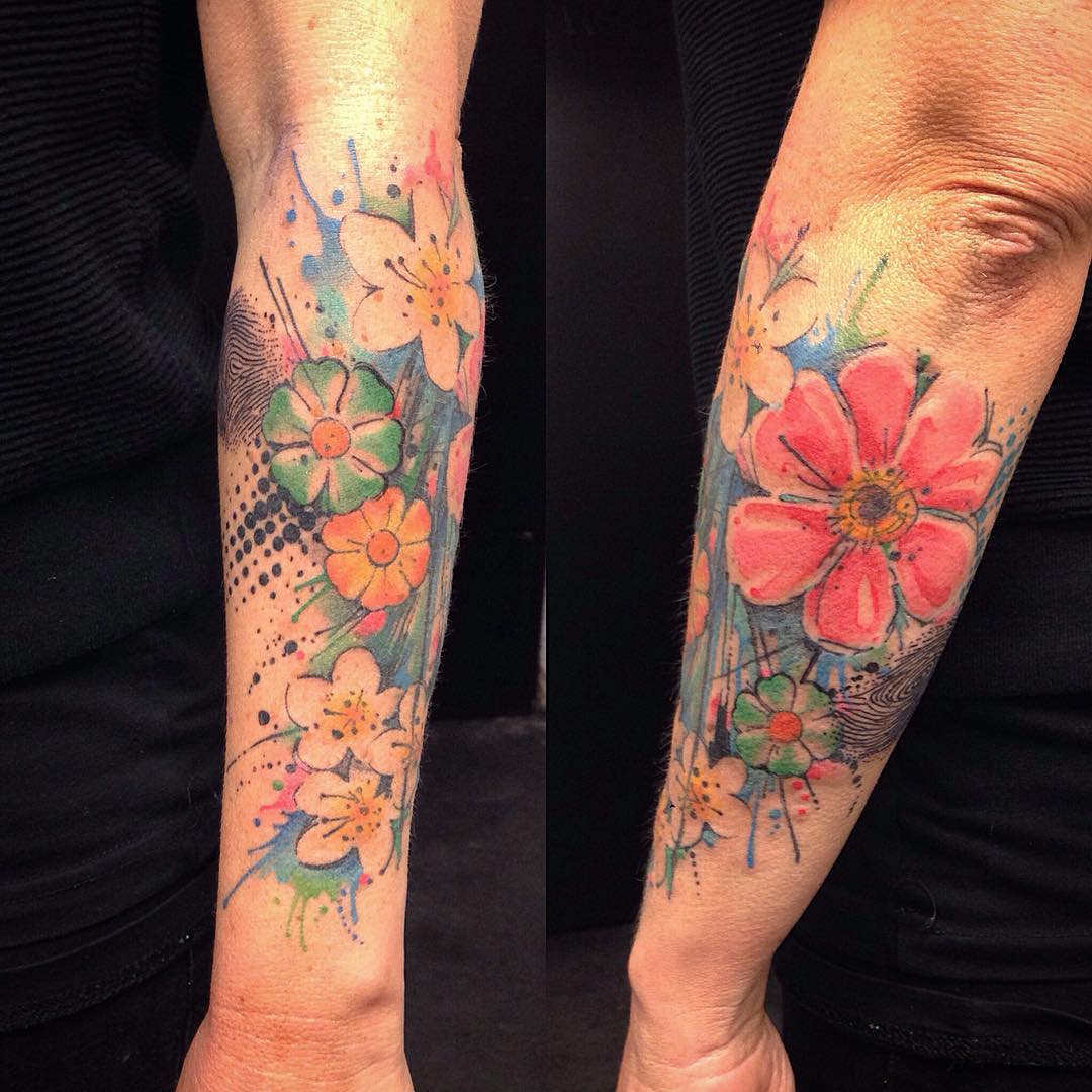 forearm decorated with many little flowers in watercolor tattoo style