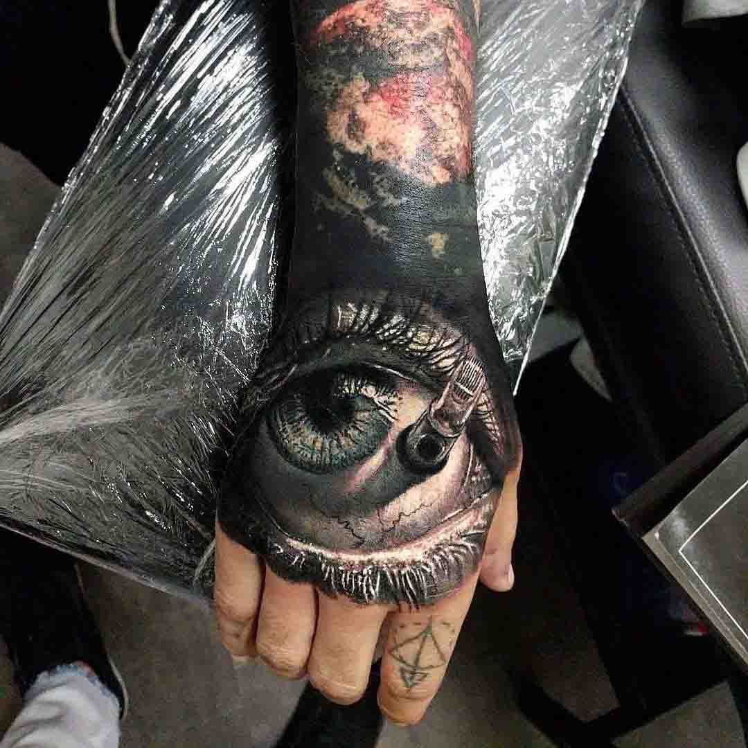 eye tattoo on hand with needles